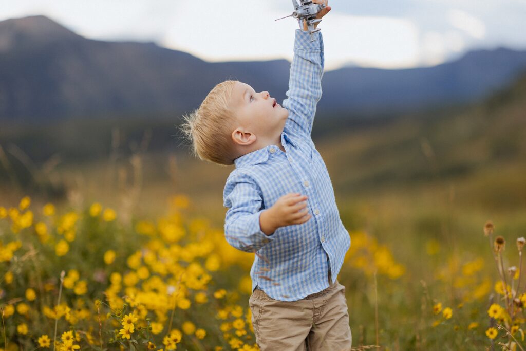 boy walking through wildflowers during a summer family session in Mt Crested Butte