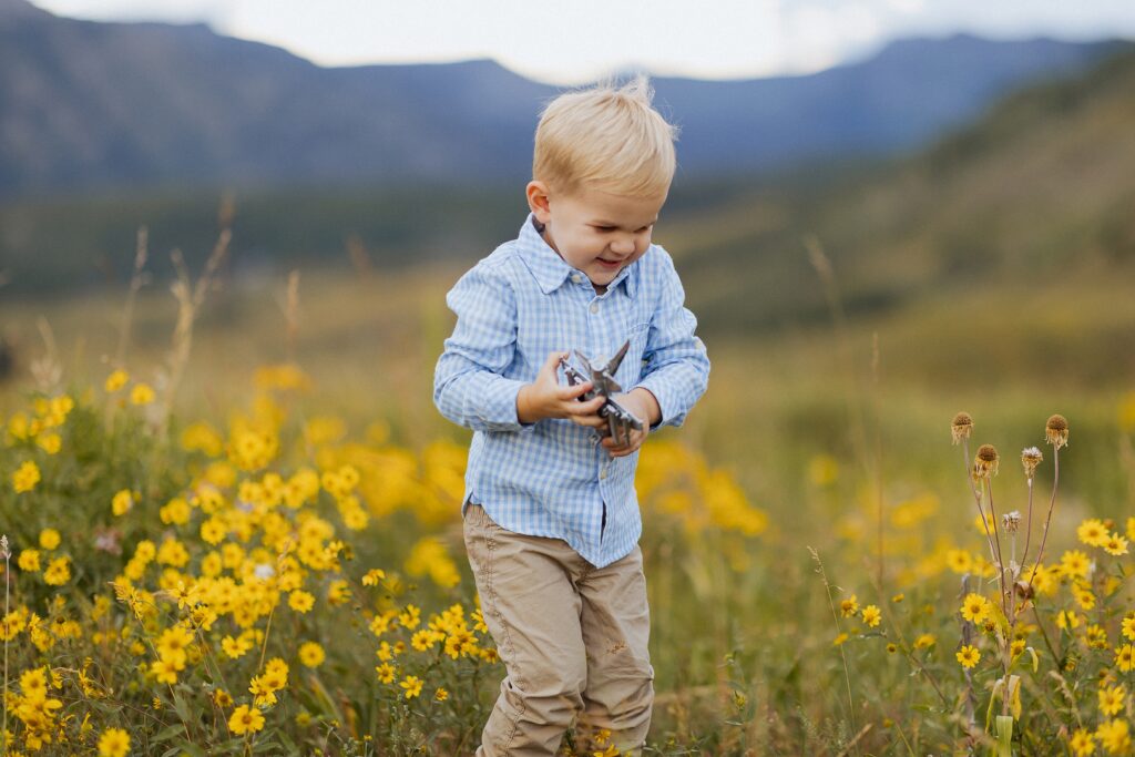 boy walking through wildflowers during a summer family session in Mt Crested Butte