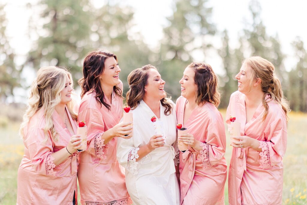 Bridesmaids in pink robes with bride toasting champagne 
