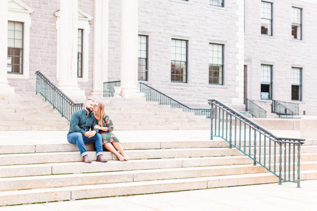 Kissing on the stairs of the city building in downtown madison after engagement 