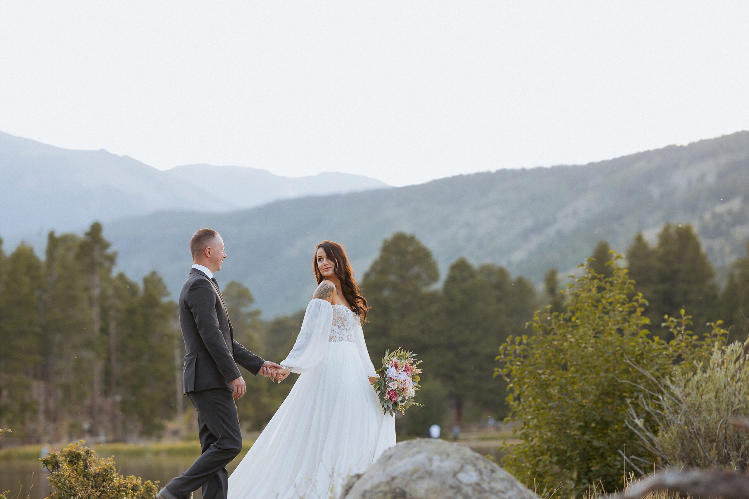 Bride and groom standing on rocks during a mountain wedding in Colorado with scenic views
