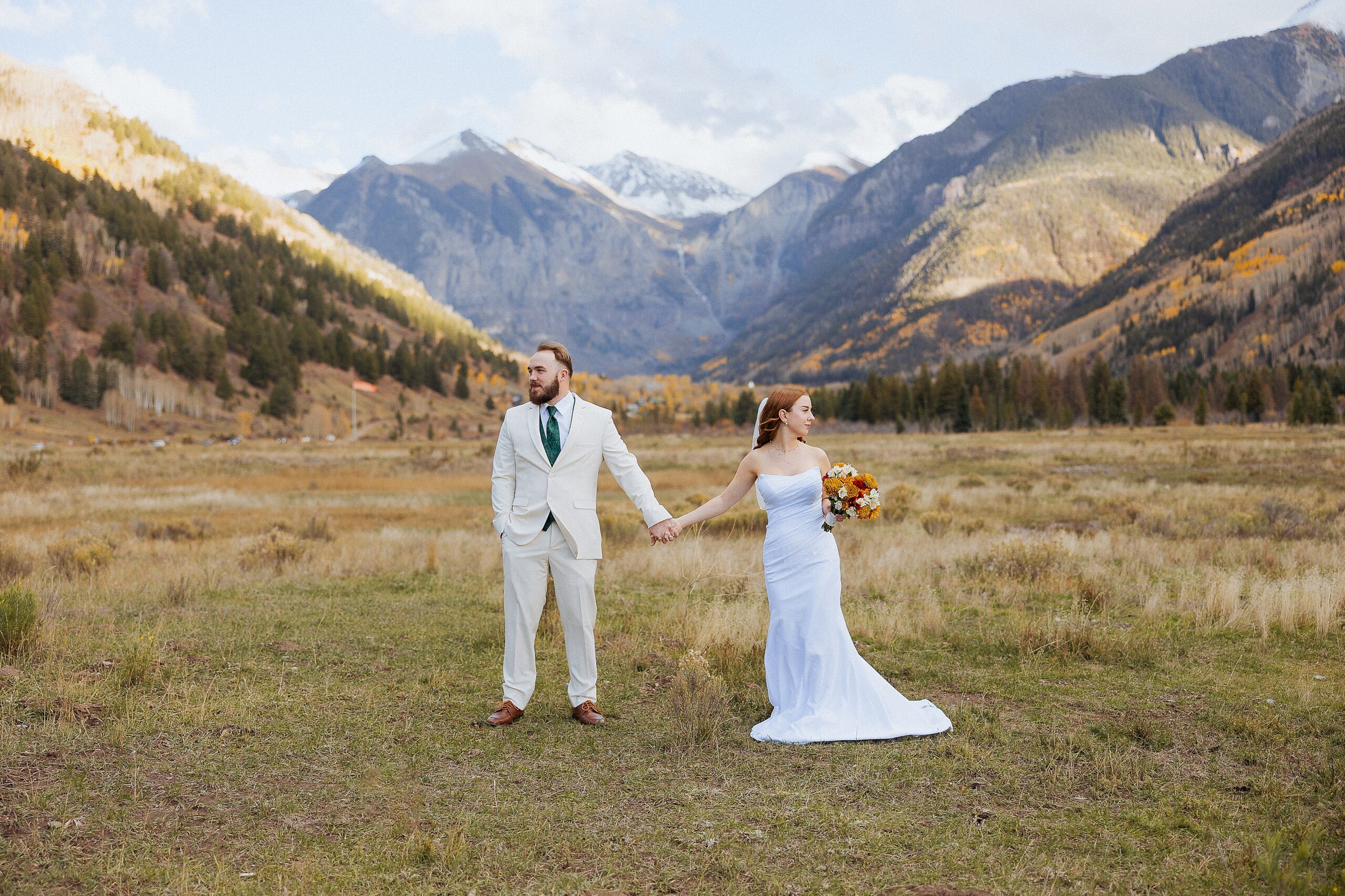 Blake and Tori walking through a mountain field during their Telluride elopement