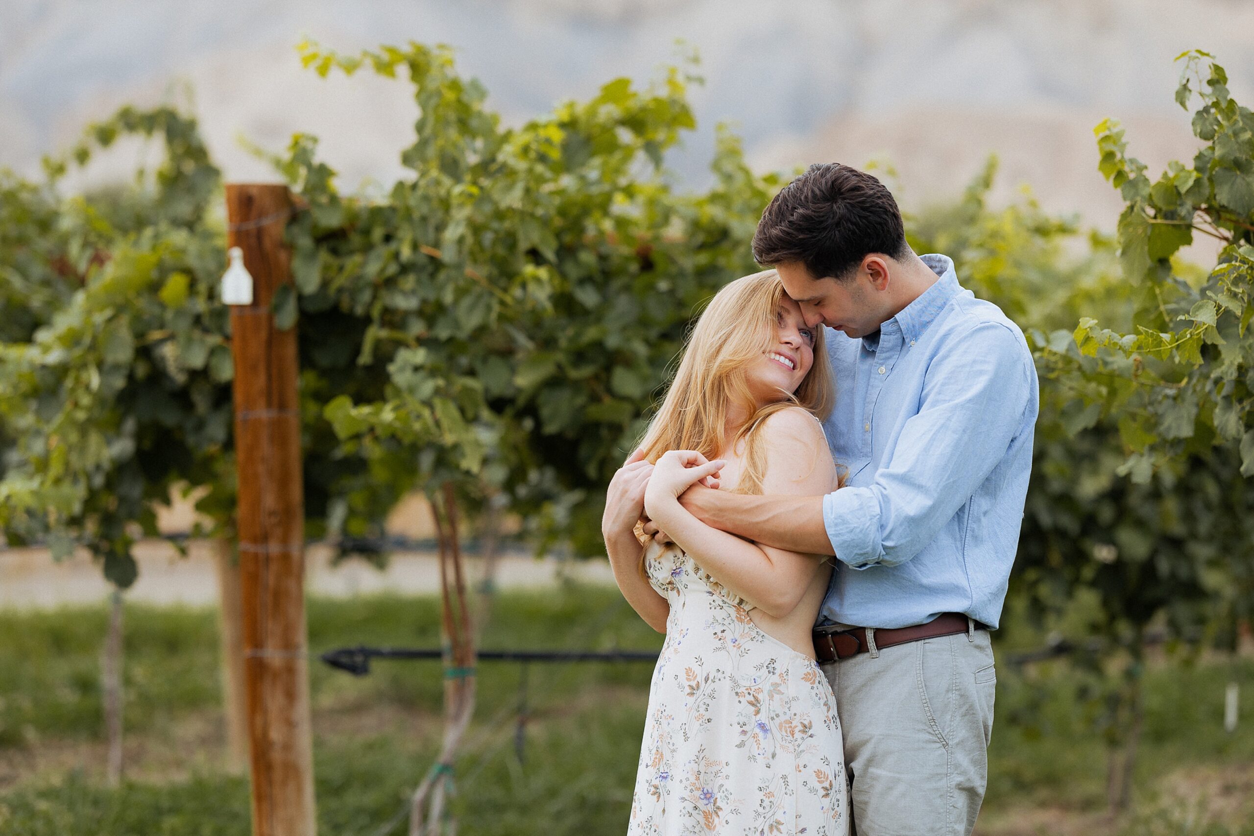 couple embracing in vineyard during Palisade Colorado engagement session at Clark and Co Distilling
