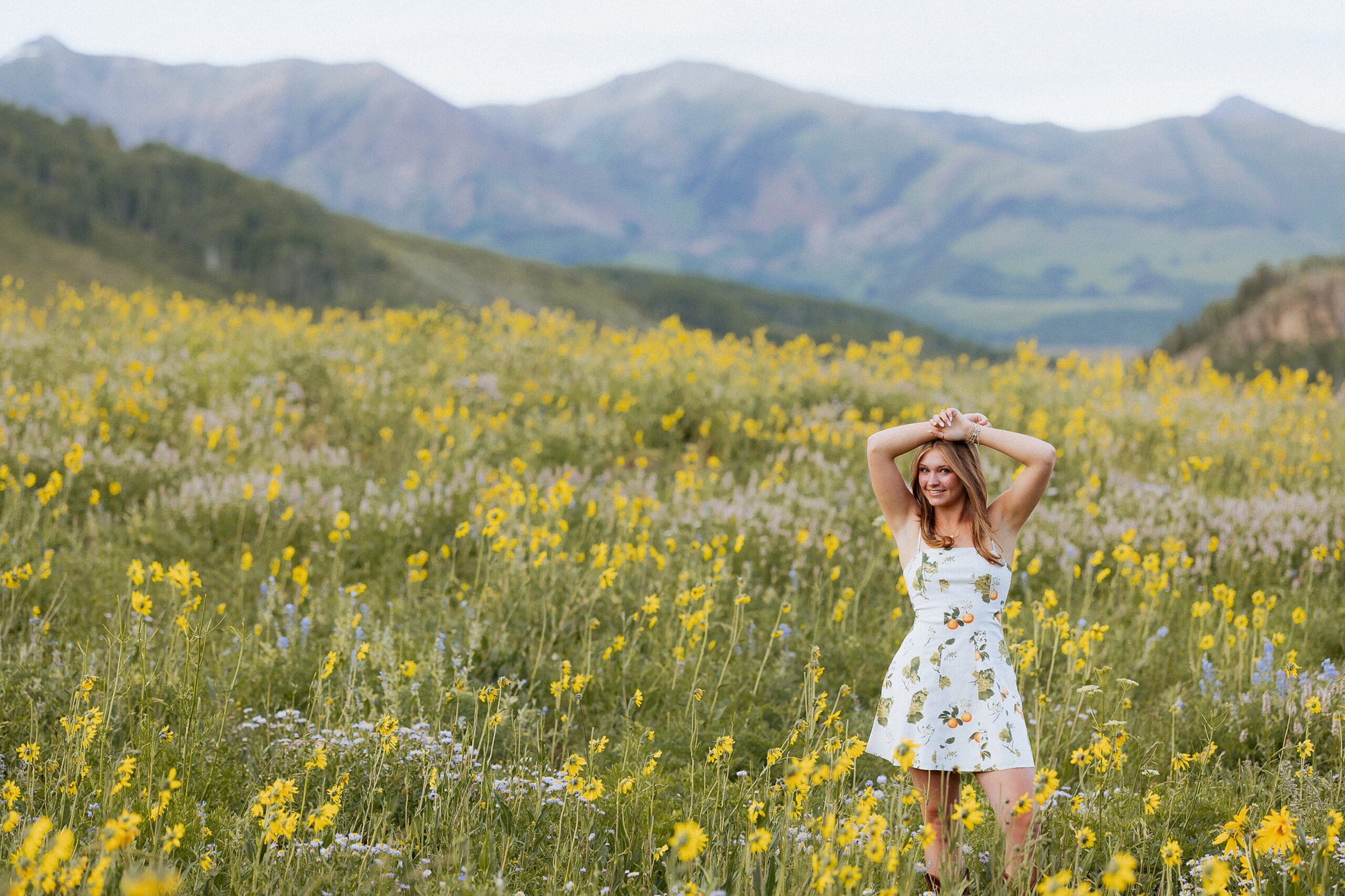 Senior girl standing in wildflowers during Crested Butte Colorado senior photo session